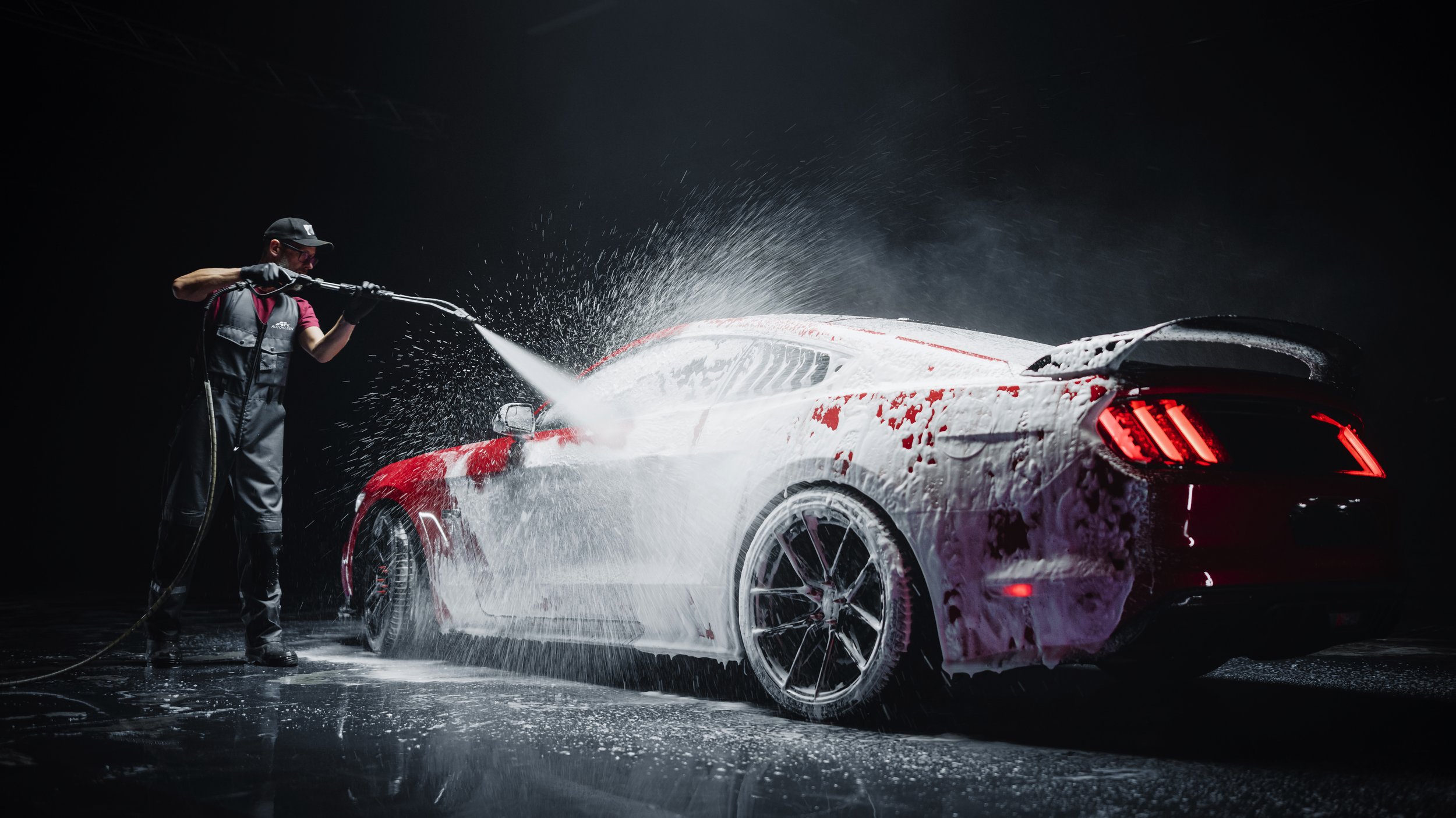 Automotive Detailer Washing Away Smart Soap and Foam with a Wate